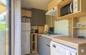 Modern kitchenette inside a glamping accommodation with stove, microwave, fridge, and dishwasher.
