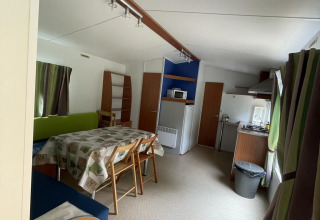 Innenansicht einer gemütlichen Hütte namens Cottage Zen auf Camping Seasonova Vesoul in Frankreich mit Esstisch.