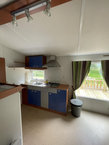 Cocina en la cabaña Cottage Zen en Camping Seasonova Vesoul, Francia, con vista a la terraza exterior.