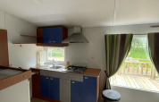 Kitchen inside the Cottage Zen cabin at Camping Seasonova Vesoul in France, showing a view of the terrace.