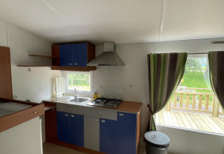 Küche in der Hütte Cottage Zen auf Camping Seasonova Vesoul in Frankreich mit Blick auf die Terrasse.