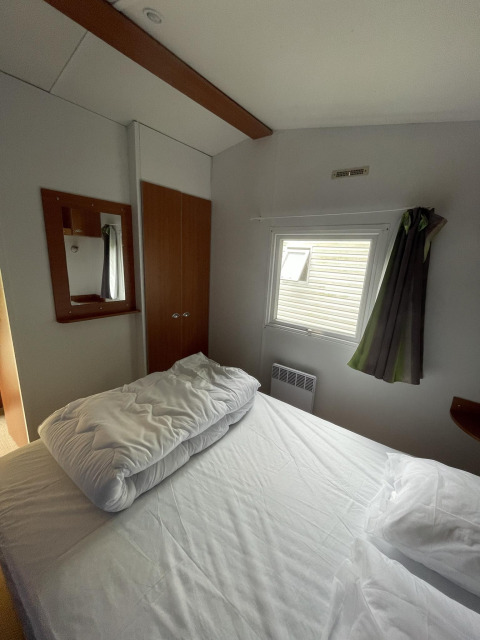 Kleine slaapkamer van Cottage Zen bij Camping Seasonova Vesoul in Frankrijk, met bed en raam.