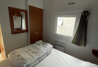 Kleines Schlafzimmer im Cottage Zen, Camping Seasonova Vesoul, Frankreich, mit Bett und Fenster.