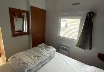 Pequeño dormitorio en Cottage Zen en Camping Seasonova Vesoul, Francia, con cama y ventana visibles.