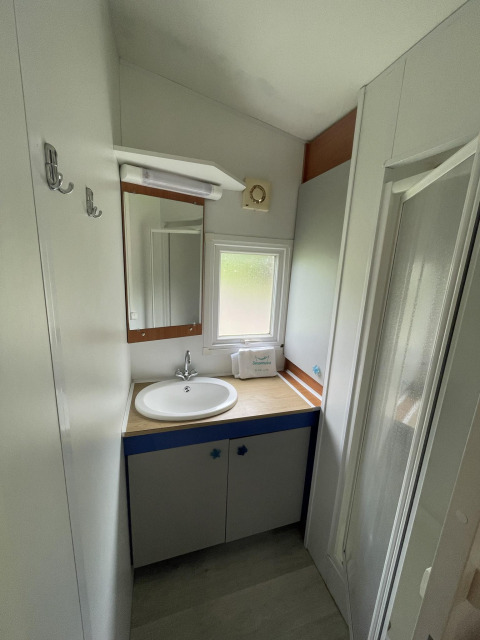 Badkamer in Cottage Zen bij Camping Seasonova Vesoul in Frankrijk met wastafel, spiegel en douche.
