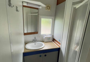 Badkamer in Cottage Zen bij Camping Seasonova Vesoul in Frankrijk met wastafel, spiegel en douche.