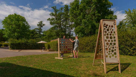 Two people play a large outdoor board game on the grass at Camping Seasonova Vittel holiday park in France.