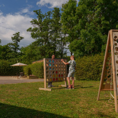 Dos personas juegan un gran juego de mesa al aire libre en el césped del Camping Seasonova Vittel en Francia.