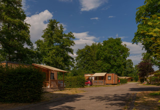 Træhytter og grønne omgivelser på Camping Seasonova Vittel feriepark i Grand Est, Frankrig på en solrig dag.