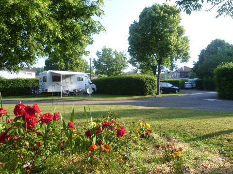 Caravana aparcada junto a flores y árboles en Camping Seasonova Vittel, Grand Est, Francia, al aire libre.