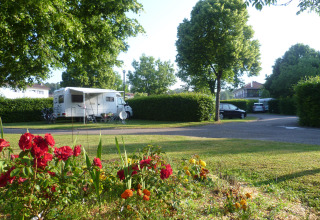 Camper met bloemenperk en bomen bij Camping Seasonova Vittel, een vakantiedomein in Grand Est, Frankrijk.
