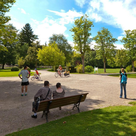 Mensen genieten van een zonnige dag in het park van Camping Seasonova Vittel, Grand Est, Frankrijk, met fietsers.