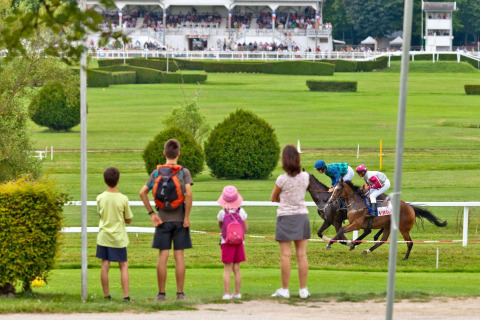 Gezin kijkt naar paardenraces bij Camping Seasonova Vittel, een vakantiepark in Grand Est, Frankrijk.