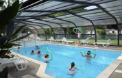 Overdækket swimmingpool med folk, der svømmer og leger med poolnudler i Camping Seasonova Les Portes d'Alsace.