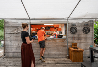 Outdoor food kiosk with guests and staff at Camping Seasonova Les Portes d'Alsace, Grand Est, France.