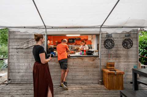Buiten eetskiosk met gasten en personeel op Camping Seasonova Les Portes d'Alsace, Grand Est, Frankrijk.