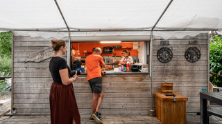 Puesto de comida al aire libre con clientes y personal en Camping Seasonova Les Portes d'Alsace, Grand Est, Francia.