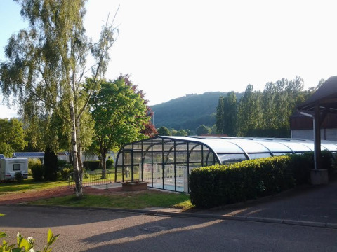 Piscina cubierta y vegetación en Camping Seasonova Les Portes d'Alsace, parque vacacional en Grand Est, Francia.