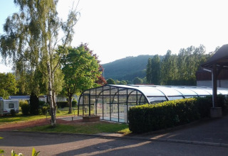 Udsigt over et overdækket svømmebassin og grønne områder ved Camping Seasonova Les Portes d'Alsace i Grand Est, Frankrig.