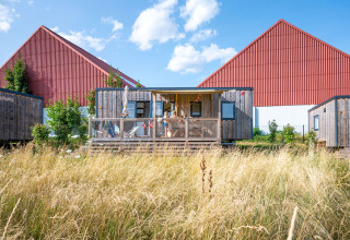 Houten chalet tussen hoog gras bij Camping Seasonova Les Portes d'Alsace, vakantiepark in Grand Est, Frankrijk.