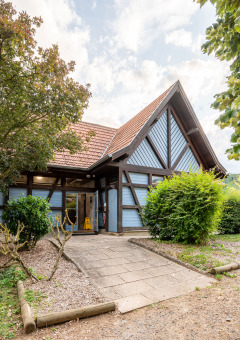 Casa con techo a dos aguas y jardín verde en Camping Seasonova Les Portes d'Alsace, parque vacacional en Francia.
