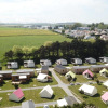 Aerial view of Camping Seasonova Etennemare in Normandy, France, showing cabins, tents, and open fields.
