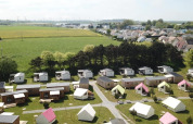 Luchtfoto van Camping Seasonova Etennemare in Normandië, met chalets, tenten en groene weides.