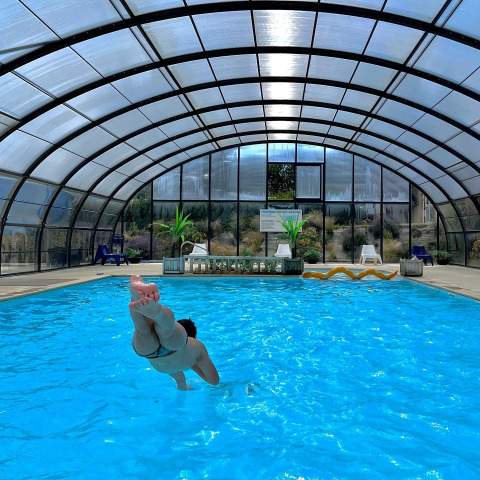 Persona saltando a una piscina cubierta en Camping Seasonova Etennemare, un parque vacacional en Normandía, Francia.