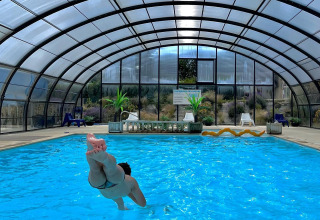 Person jumping into an indoor pool at Camping Seasonova Etennemare, a holiday park in Normandy, France.