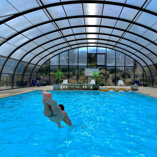 Persoon springt in een overdekt zwembad bij Camping Seasonova Etennemare, een vakantiepark in Normandië, Frankrijk.