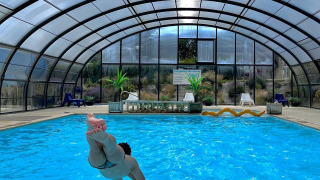 Persona saltando a una piscina cubierta en Camping Seasonova Etennemare, un parque vacacional en Normandía, Francia.