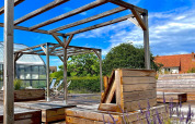 Outdoor glamping area with wooden terrace, seating benches, blooming lavender and a clear blue sky.
