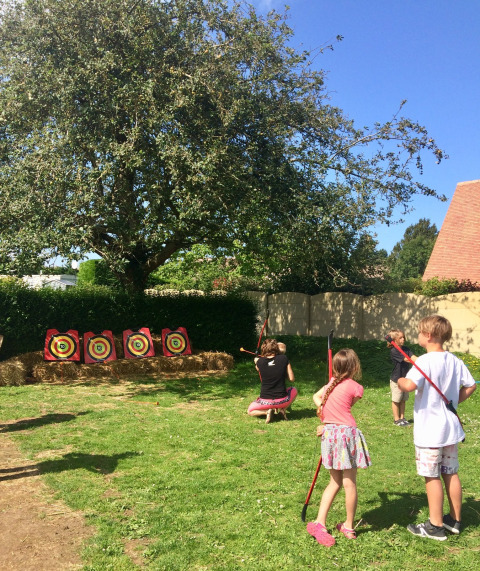 Niños practicando tiro con arco al aire libre en Camping Seasonova Etennemare en Normandía, Francia.