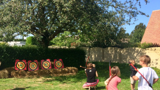 Niños practicando tiro con arco al aire libre en Camping Seasonova Etennemare en Normandía, Francia.