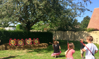 Niños practicando tiro con arco al aire libre en Camping Seasonova Etennemare en Normandía, Francia.