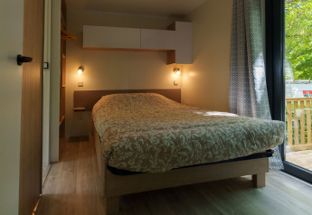 Komfortabelt soveværelse i lodge med dobbeltseng, moderne indretning og udsigt til træterrasse.