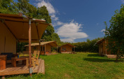Foto de las tiendas safari Slow Lodge en Camping Seasonova Vittel, Francia, rodeadas de naturaleza y árboles.