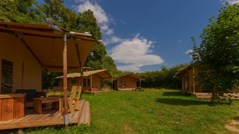 Foto de las tiendas safari Slow Lodge en Camping Seasonova Vittel, Francia, rodeadas de naturaleza y árboles.