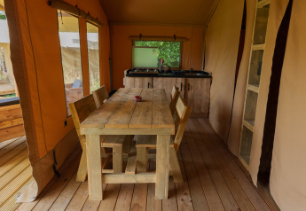 Binnenkant van de safaritent Slow Lodge bij Camping Seasonova Vittel in Frankrijk met houten meubels en keuken.