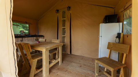 Interior de la tienda safari Slow Lodge en Camping Seasonova Vittel, Francia, con muebles de madera y cocina.