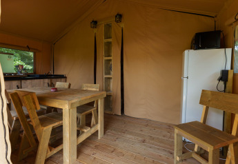 Interior de la tienda safari Slow Lodge en Camping Seasonova Vittel, Francia, con muebles de madera y cocina.