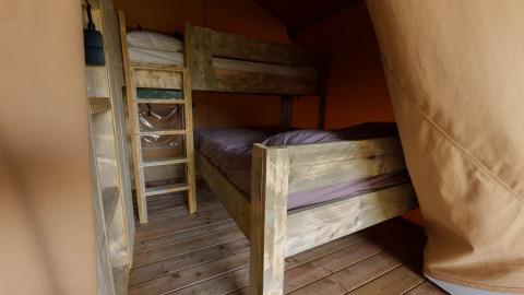 Houten stapelbedden in een safaritent bij Slow Lodge, Camping Seasonova Vittel, Frankrijk met houten vloer.