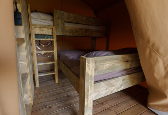 Houten stapelbedden in een safaritent bij Slow Lodge, Camping Seasonova Vittel, Frankrijk met houten vloer.