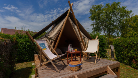 Tienda safari Bivouac Nomade en Camping Seasonova Vittel, Francia con terraza de madera y sillas.