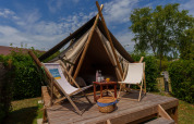 Tienda safari Bivouac Nomade en Camping Seasonova Vittel, Francia con terraza de madera y sillas.