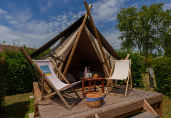 Tenda safari Bivouac Nomade al Camping Seasonova Vittel in Francia con terrazza in legno e sedie.