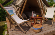 Safaritent Slow Life Stay bij Camping Seasonova Vittel in Frankrijk met zetels, tafeltje en picknickmand.