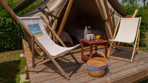 Tienda safari Slow Life Stay en Camping Seasonova Vittel en Francia, con sillas, mesa y cesta de picnic.