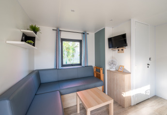 Bright, modern living room in Cottage Prestige at Camping Seasonova Les Portes d'Alsace with sofa and TV.