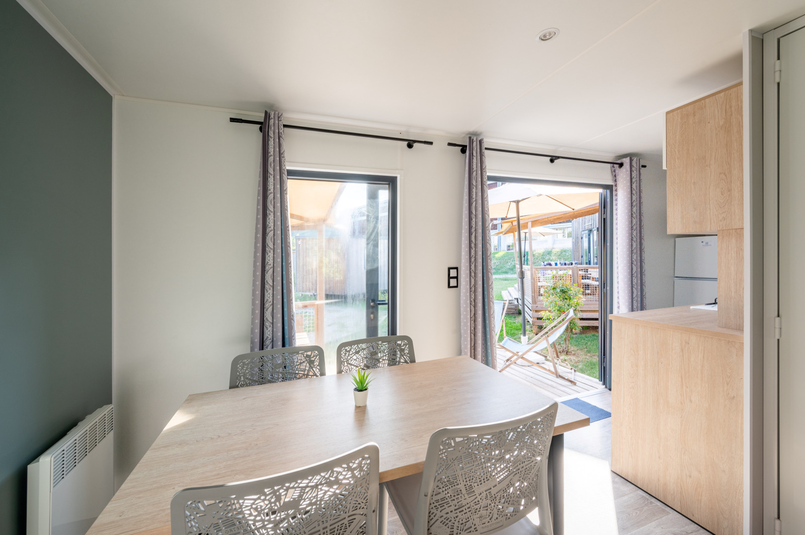 Lichte eetruimte in Cottage Prestige op Camping Seasonova Les Portes d'Alsace met uitzicht op terras.